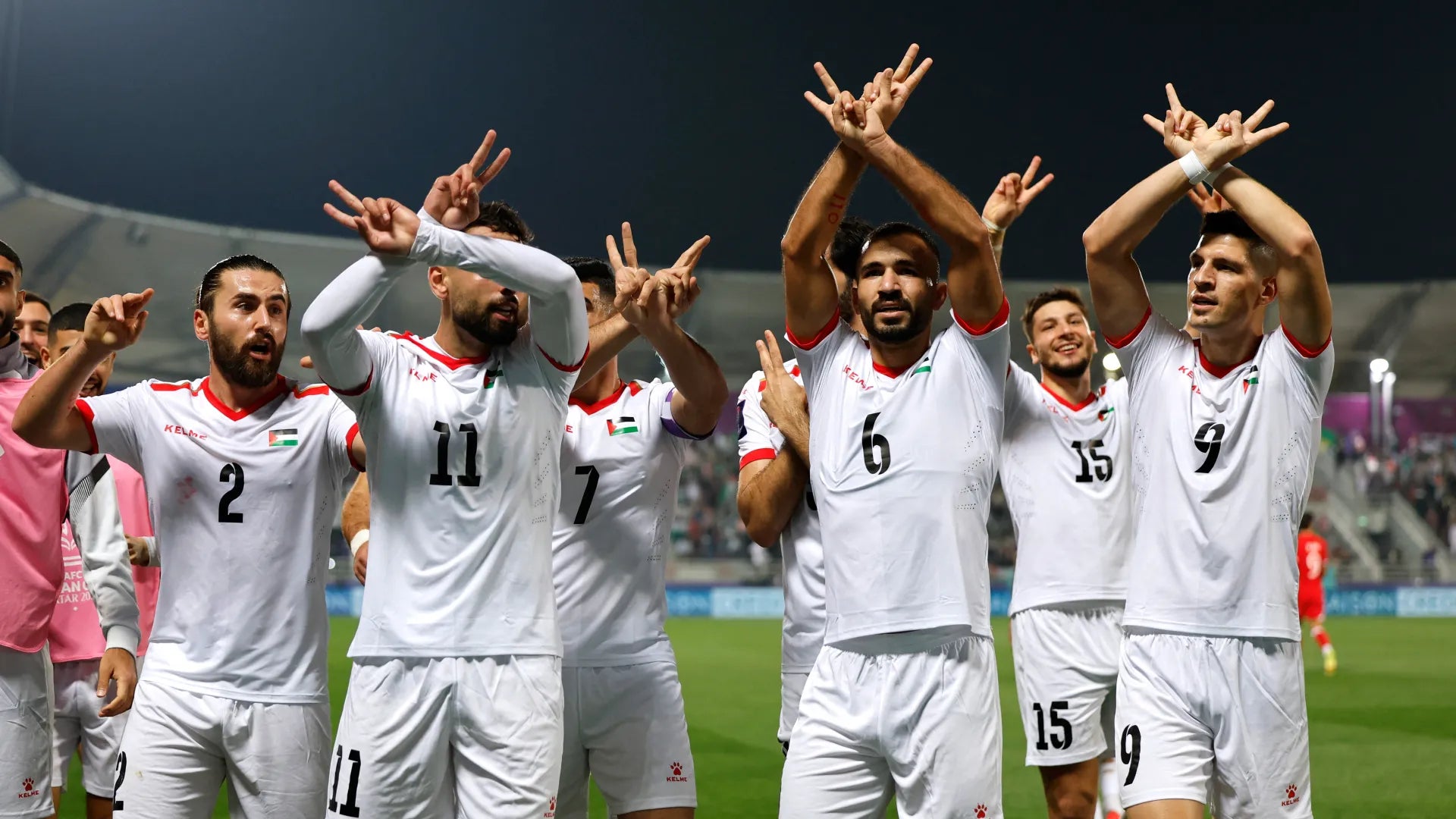 Palestine national team players wearing jersey and throwing freedom and resistance hand signs after victory in the AFC cup